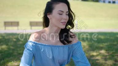 一幅漂亮的黑发女人坐在公园里的蓝色裙子